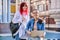 Two teenage female students using outdoor laptop, city street background