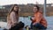 Two teenage girl sitting in the wooden deck chairs on the lake shore