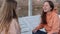 Two teenage girl sitting in the wooden deck chairs on the lake shore