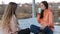 Two teenage girl sitting in the wooden deck chairs on the lake shore