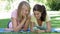 Two Teenage Girls Lying In Garden Reading Text Message