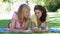 Two Teenage Girls Lying In Garden Reading Text Message