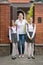 Two teenage girls posing with mother in front of big house before going to school