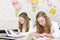 Two teenage girls studying in front of wall world chart