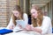 Two teenage girls studying in long school corridor