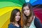 Two teenage girls under rainbow umbrella