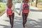 Two teenage girls walk in city on autumn day in summer, hold hands, look from back, casual clothes, jeans and a sweater