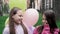 two teenage school girls having fun outdoors. in colourful clothes near hot air balloons. friendship, sisterhood