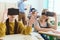 Two teenage schoolgirls using virtual reality headsets and classmate with teacher