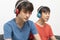 Two teenager boys listening to music with headphones in living room.