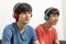 Two teenager boys listening to music with headphones in living room.
