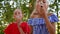 Two teenager girls blowing to white dandelion in summer park. Girls blowing taraxacum front camera in green park. Girls