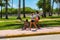 Two teenager girls in face mask walking outdoor with Afro-American boy rides a bicycle