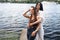 Two teenager girls sitting on a pier at the river bank having good time in summer. happy girl friends relaxing outdoor near lake.