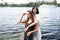 Two teenager girls sitting on a pier at the river bank having good time in summer. happy girl friends relaxing outdoor near lake.