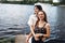 Two teenager girls sitting on a pier at the river bank having good time in summer. happy girl friends relaxing outdoor near lake.