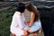 Two teenager girls sitting on a pier at the river bank having good time in summer. happy girl friends relaxing outdoor near lake.