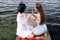 Two teenager girls sitting on a pier at the river bank having good time in summer. happy girl friends relaxing outdoor near lake.