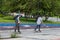 Two teenager guys with regrown hair ride on skateboards in the summer in the park on a specially allocated asphalt strip with