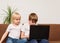 Two teenagers sitting on couch and look at laptop. Video lessons for kids concept