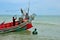 Two Thai fishermen prepare boat with anchor at seaside Pattani Thailand