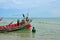 Two Thai fishermen prepare boat with anchor at seaside Pattani Thailand
