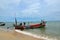 Two Thai fishermen take equipment onto boat at seaside Pattani Thailand