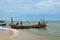 Two Thai fishermen take equipment onto boat at seaside Pattani Thailand