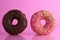 Two or three doughnut berliner pink yellow chocolate on a pink background stand falling there is room for text and with a