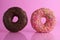 Two or three doughnut berliner pink yellow chocolate on a pink background stand falling there is room for text and with a