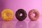 Two or three doughnut berliner pink yellow chocolate on a pink background stand falling there is room for text and with a