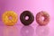 Two or three doughnut berliner pink yellow chocolate on a pink background stand falling there is room for text and with a
