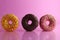 Two or three doughnut berliner pink yellow chocolate on a pink background stand falling there is room for text and with a