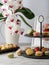 Two tier cake stone stand with tasty french macarons and orchid on marble table.