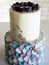 Two-tier cream cake in blue-gray-lilac colors, decorated with blueberries and sprigs of lavender on black stand. Wedding