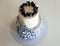 Two-tier cream cake in blue-gray-lilac colors, decorated with blueberries and sprigs of lavender on black stand. Wedding