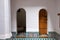 Two tiny wooden doors, one closed the other open on an Arabian style with white walls room