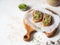 Two toasts chicken rillettes pate on white bread with sprouts on white plate on a wood cutting board
