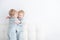 Two toddler baby twin boys in pajamas hugging at home on white background