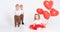 Two toddler boys in suits looking on little girl with heart balloons on white background