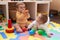 Two toddlers playing with toys sitting on floor at kindergarten