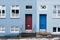 A two-tone building in blue and light blue with two rectangular doors in blue and burgundy and windows of different