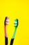 Two toothbrushes pink and green on a yellow background, oral hygiene