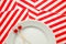 Two toothpicks with small red hearts on a white plate and on a background of striped holiday napkins