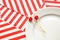 Two toothpicks with small red hearts on a white plate and on a background of striped holiday napkins