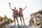 Two tourist male and woman with backpacks stand to the top of the crag and enjoying sunrise. Traveling mountains and