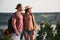 Two tourist male and woman with backpacks stand to the top of the crag and enjoying sunrise. Traveling mountains and