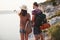 Two tourist male and woman with backpacks stand to the top of the crag and enjoying sunrise. Traveling mountains and