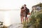 Two tourist male and woman with backpacks stand to the top of the crag and enjoying sunrise. Traveling mountains and