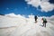 Two tourists, a man and a woman with backpacks and crampons on their feet walk along the glacier against the background